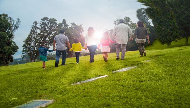 Three generations of a family walk toward the sun on a visit to their place of remembrance. 
